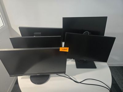 three monitors sitting on a table in front of a window