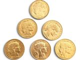 six gold sovereigns are arranged in a pyramid on a white surface