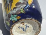 a blue and yellow vase sitting on a white surface