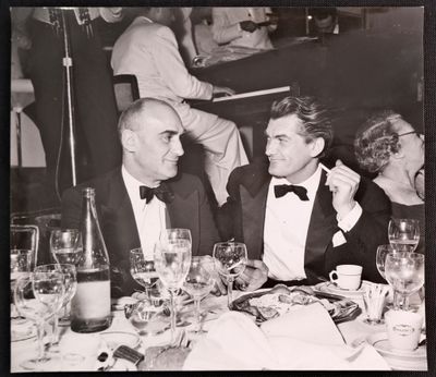 black and white photograph of two men sitting at a table with wine glasses