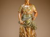 bronze statue of a woman standing on a rock with her hands in her pockets