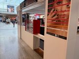 lobby of a mall with a display of cosmetics products and people walking by