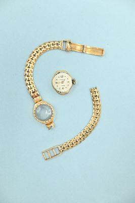 une montre en or et un bracelet sur un fond bleu