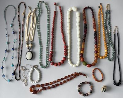 many different necklaces and bracelets laid out on a table
