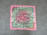 un foulard carré à motifs floraux roses et verts accroché à un mur