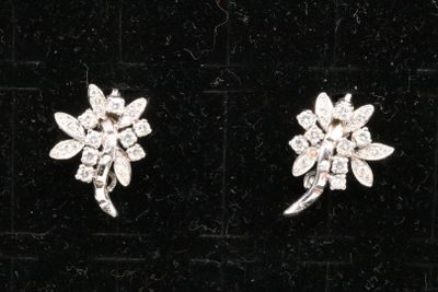 two pairs of diamond earrings on a black velvet surface