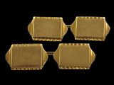 a set of four gold plated cufflinks on a black background