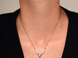 La femme porte un t-shirt noir et un collier de diamants autour du cou.