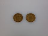 two gold coins sitting side by side on a white surface