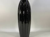 the black vase is sitting on a white surface