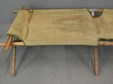 a small wooden bench with a tan cover on it