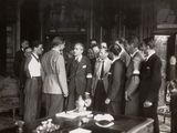 many men standing in a room talking to each other