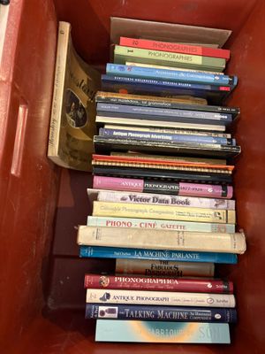 many books stacked in a red box on the floor