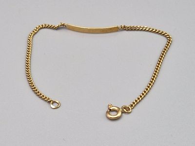 un gros plan d'un bracelet en or muni d'un fermoir, posé sur une surface blanche
