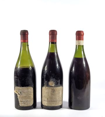 trois bouteilles de vin posées les unes à côté des autres sur une surface blanche