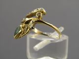 gros plan d'une bague en or avec une pierre verte