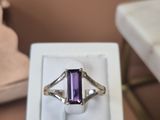 une bague sertie d'une pierre violette, posée sur une boîte blanche