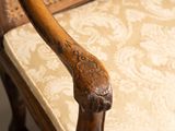 an old chair with a wooden arm rest and a beige cushion
