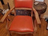 a wooden chair with an orange seat in a room