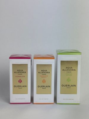 three boxes of perfume sitting next to each other on a white surface