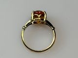 a gold ring with an orange stone on it