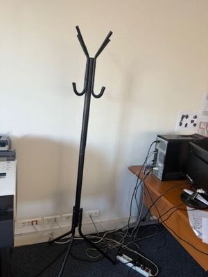 a desk with a printer and a coat rack in the corner