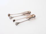 three silver spoons sitting on top of each other on a white surface