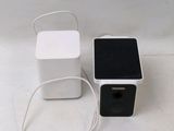 two speakers and a charger on a white surface