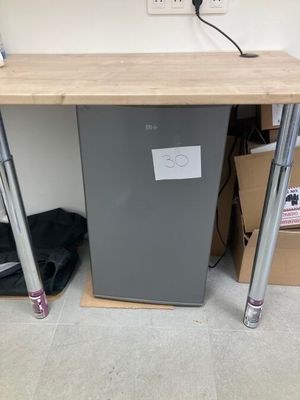 a small refrigerator sitting under a desk in a room