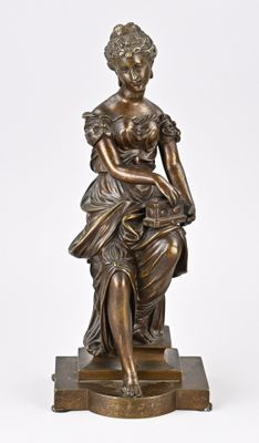 une statue antique en bronze représentant une femme assise sur un socle