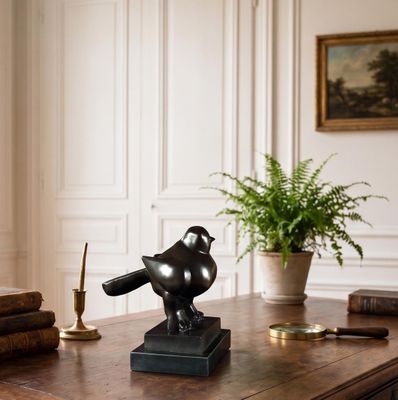 a statue of a bird sitting on top of a desk