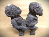 a stone sculpture of two people sitting on the ground