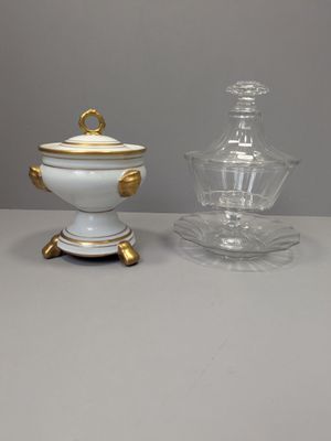 deux vases blancs et dorés posés sur une table, à côté d'un bocal en verre