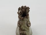 a small vase with a face on it on a white surface