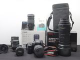 a lot of cameras and lenses on the table