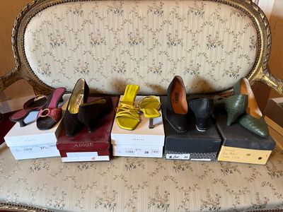 several pairs of women ' s shoes sitting on top of boxes on a chair