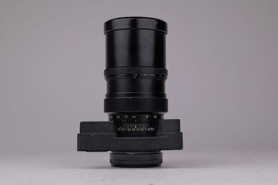 un gros plan sur l'objectif noir d'un appareil photo posé sur une surface blanche