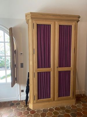 une grande armoire en bois avec des rideaux violets dans une pièce