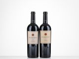 two bottles of red wine sitting on top of a table
