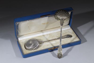 une cuillère en argent et un repose-cuillère dans une boîte bleue