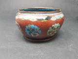 a red bowl with blue flowers on it on a table