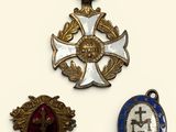 three medals are displayed on a white surface, including a cross, a medal, and a medal