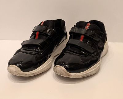 une paire de chaussures noires pour enfants à semelles blanches posées sur une surface blanche