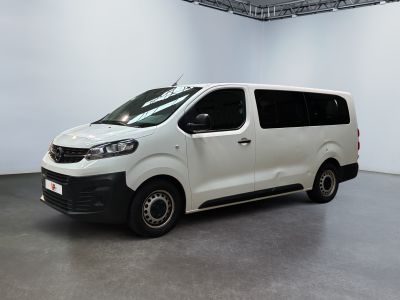 La camionnette blanche est garée dans une grande pièce aux murs blancs.