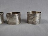 three silver napkins with designs on them sitting on a table