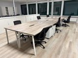 une longue table avec des chaises et un ordinateur portable posé dessus, dans un bureau