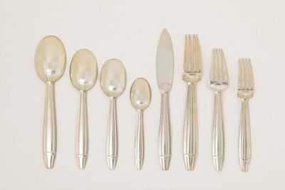 five forks, a spoon, and a knife on a white surface