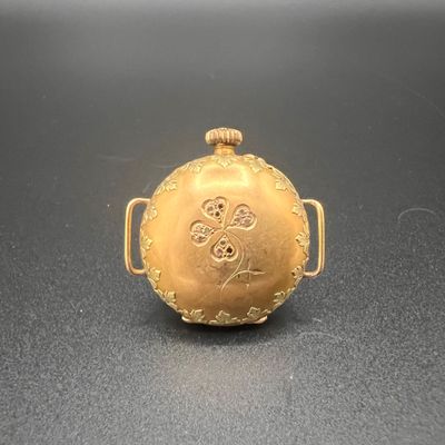 une montre de poche en or posée sur une table, sur fond noir