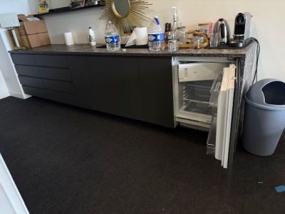 une photo d'une cuisine avec un réfrigérateur et une poubelle