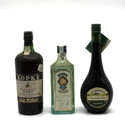 trois bouteilles d'alcool posées les unes à côté des autres sur une surface blanche